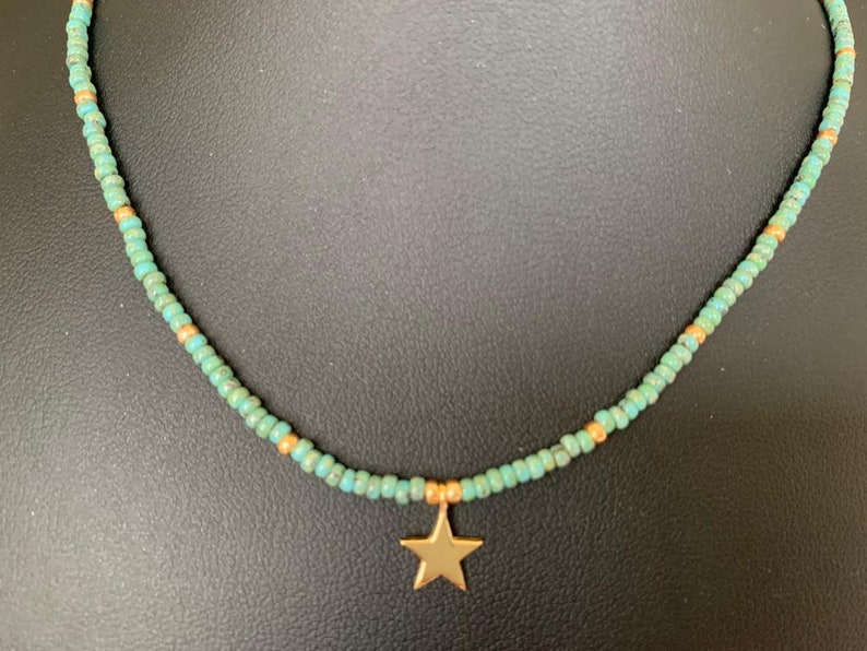 May include: A turquoise and gold beaded necklace with a gold star pendant.