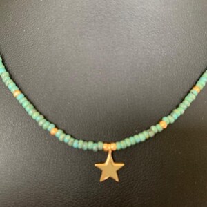 May include: A turquoise and gold beaded necklace with a gold star charm.