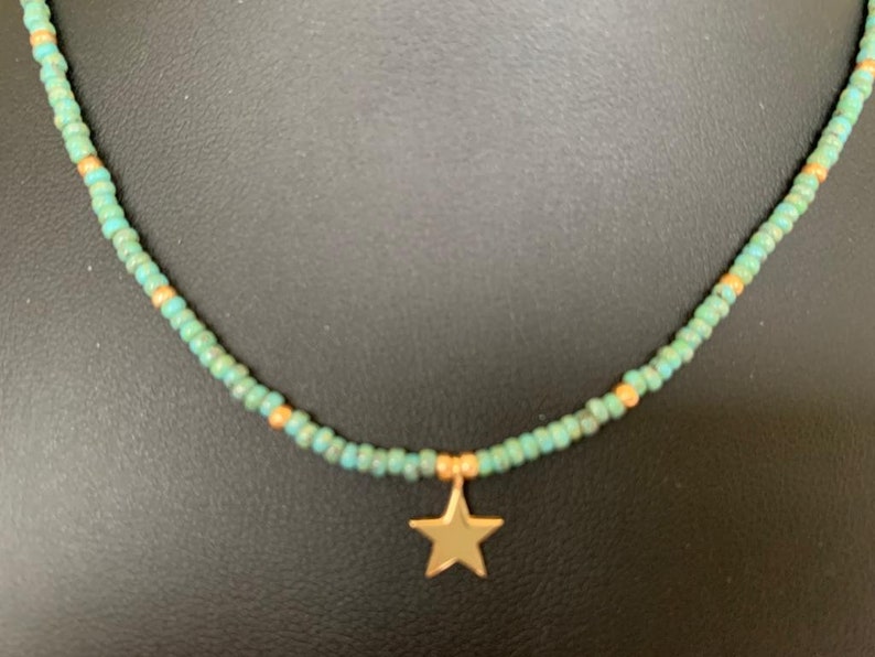 May include: A turquoise and gold beaded necklace with a gold star charm.