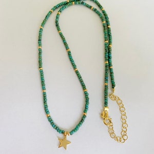 May include: A delicate gold chain necklace with turquoise beads and a gold star charm. The necklace has an adjustable length.