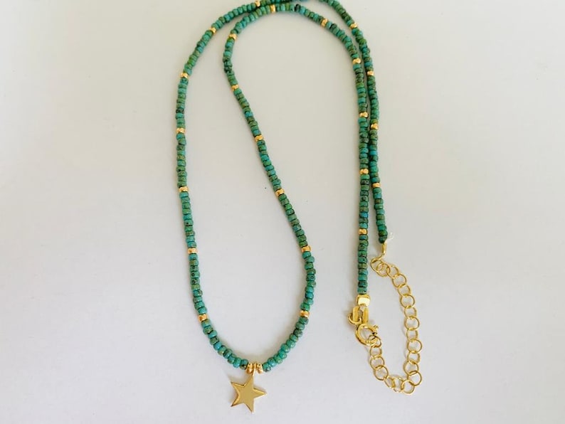 May include: A delicate gold chain necklace with turquoise beads and a gold star charm. The necklace has an adjustable length.