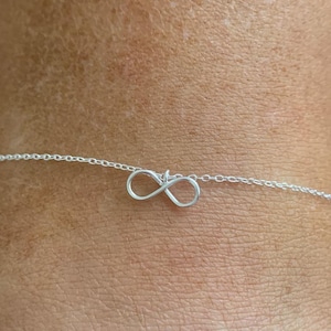 May include: A silver anklet with a delicate chain featuring an infinity symbol.