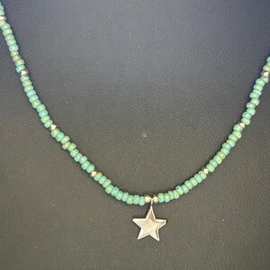May include: A turquoise beaded necklace with a silver star charm.