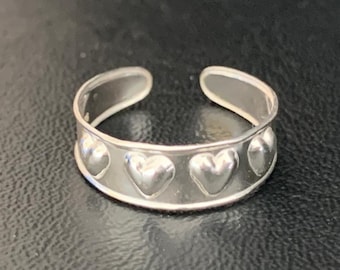 May include: Silver toe ring with a band of hearts. The ring is adjustable and has a smooth finish.