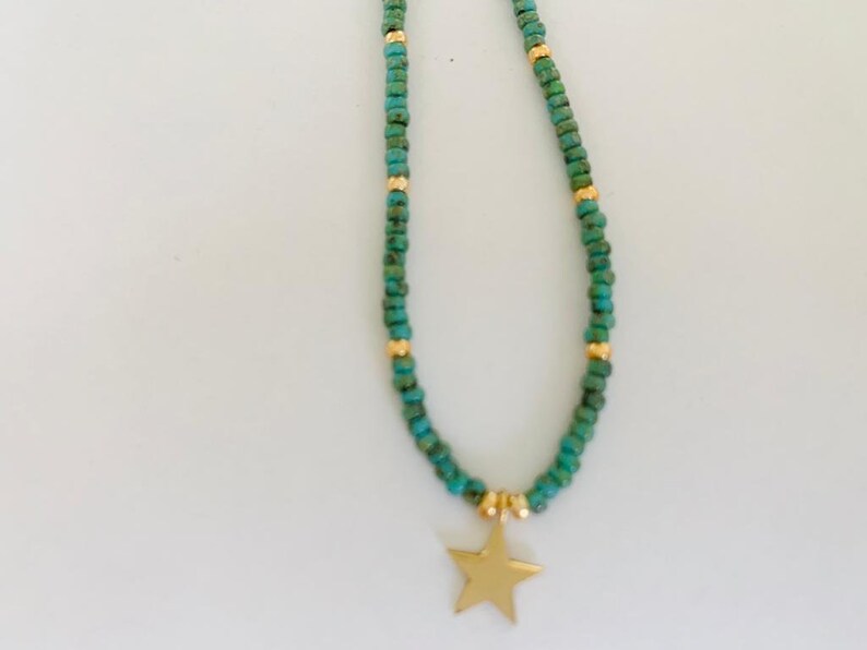 May include: A turquoise and gold beaded necklace with a gold star charm.