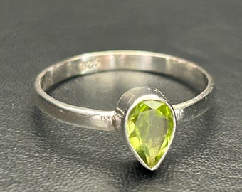 Op de afbeelding: Een zilveren ring met een peervormige groene edelsteen.