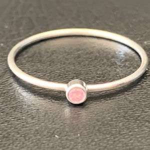 May include: A simple silver band ring with a small pink opal gemstone.