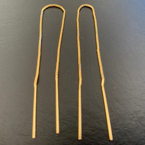 May include: A pair of gold chain earrings with long, thin, straight drops.
