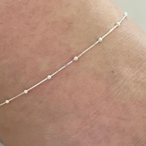 May include: A silver anklet with small round beads.