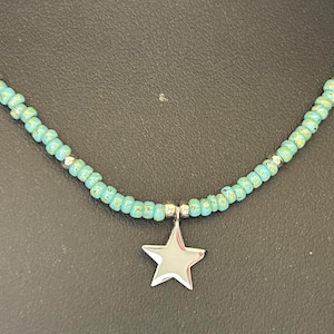 May include: A turquoise beaded necklace with a silver star charm.