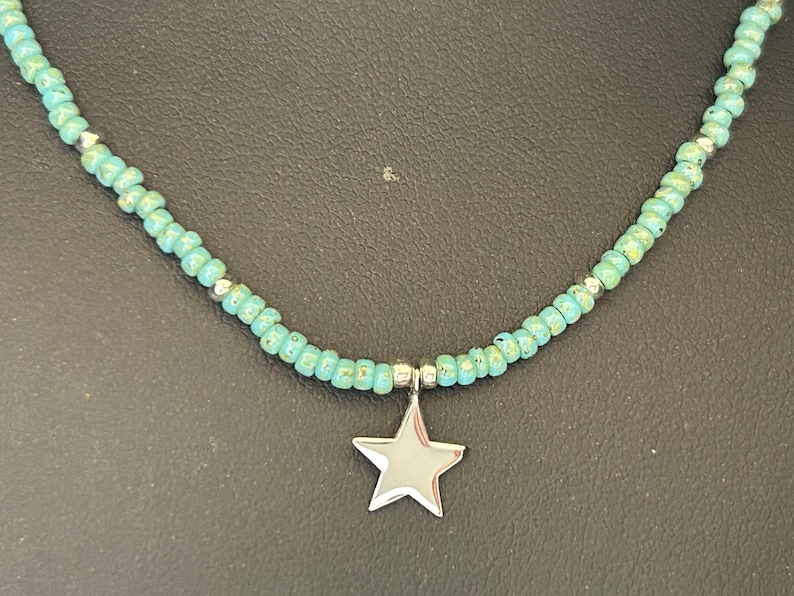 May include: A turquoise beaded necklace with a silver star charm.