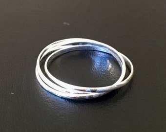 May include: A set of four silver rings, each with a slightly different width, are stacked together. The rings are smooth and shiny.