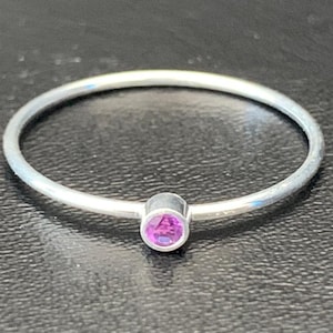 May include: A simple silver ring with a small, round, purple gemstone.