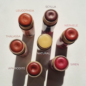 Puede incluir: Siete b&aacute;lsamos labiales diferentes en una variedad de colores, incluyendo rojo, marr&oacute;n y amarillo. Los b&aacute;lsamos labiales est&aacute;n en tubos con etiquetas que incluyen los nombres: Scylla, Leucothea, Nephele, Thalassa, Natural, Aphrodite y Siren.