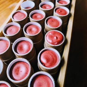 Nephele tinted lipbalms freshly poured into their compostable tubes, before their lids are put on, labelled and shipped out.