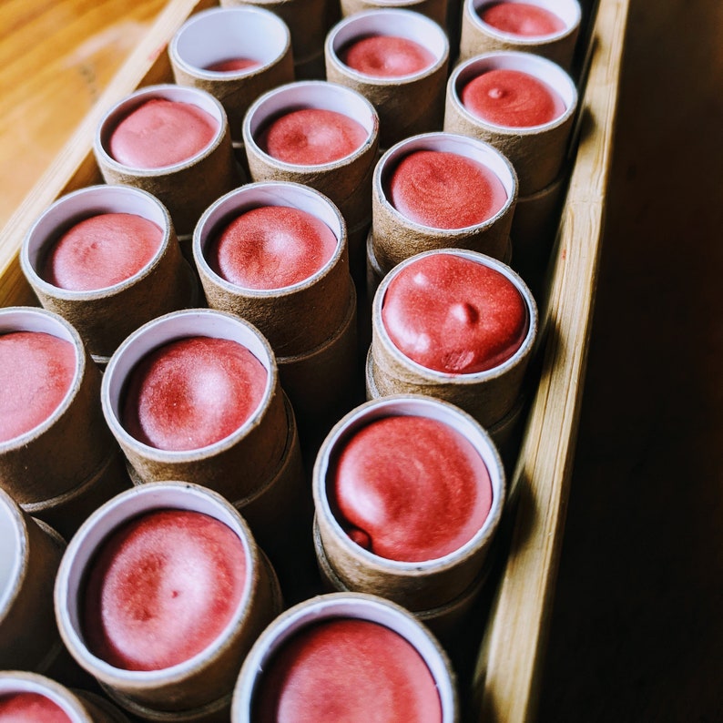 Nephele tinted lipbalms freshly poured into their compostable tubes, before their lids are put on, labelled and shipped out.