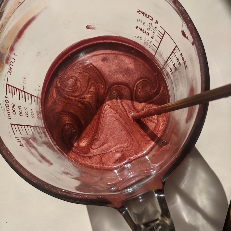 Tinted lip balms in the making (in the shade Nephele, a lovely peachy pink). A top view of the mixture before pouring showing the beautiful swirls from the shimmery pigments in the molten balm