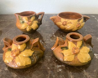 vintage Roseville Pottery creamer, sugar bowl, and a pair of candle holders in the Clematis pattern.