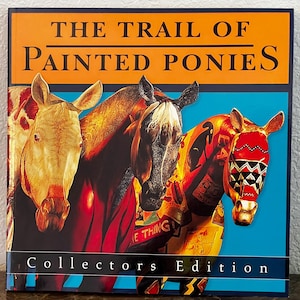 May include: A book cover titled "The Trail of Painted Ponies" with a blue background and orange header. The cover features four painted pony heads in shades of brown, red, and yellow. The words "Collectors Edition" are at the bottom.