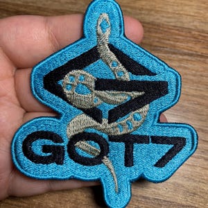 May include: A blue and black embroidered patch with a snake design and the text "GOT7".