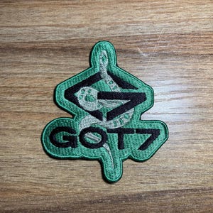 May include: Green embroidered patch with a snake design and the text "GOT7" in black.