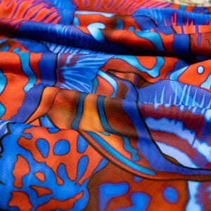 May include: A close-up of a blue and orange fabric with a swirling, abstract pattern. The fabric has a soft, flowing texture and is perfect for creating unique garments or home decor.