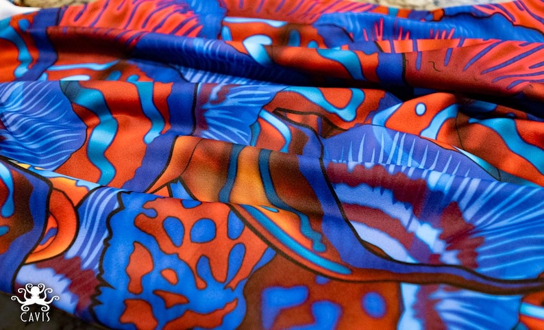 May include: A close-up of a blue and orange fabric with a swirling, abstract pattern. The fabric has a soft, flowing texture and is perfect for creating unique garments or home decor.