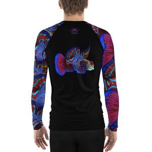 May include: A black long-sleeve rash guard with a colorful fish design on the back and sleeves. The fish is red, blue, and orange with a white outline. The rash guard has the word "CAVIS" printed on the back in purple.