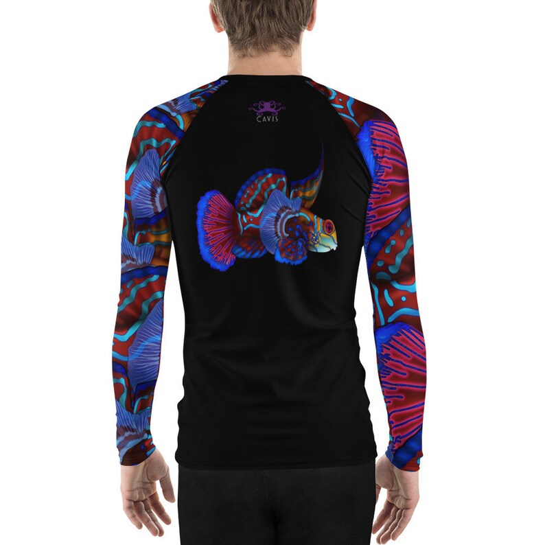 May include: A black long-sleeve rash guard with a colorful fish design on the back and sleeves. The fish is red, blue, and orange with a white outline. The rash guard has the word "CAVIS" printed on the back in purple.