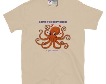 Puede incluir: Camiseta beige con un diseño de pulpo de dibujos animados. El texto encima del pulpo dice "I GIVE THE BEST HUGS!" y debajo, "If you survive...". El pulpo es naranja con corazones rojos y ojos azules.