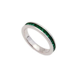 May include: A silver ring with a band of emerald green stones.