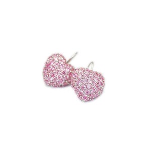 May include: A pair of heart-shaped earrings. Each earring is covered in small, pink gemstones. The earrings have a silver-colored hook. The background is white.