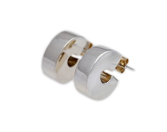 May include: A pair of silver hoop earrings with a rounded, slightly curved shape. The earrings are made of a smooth, polished metal.