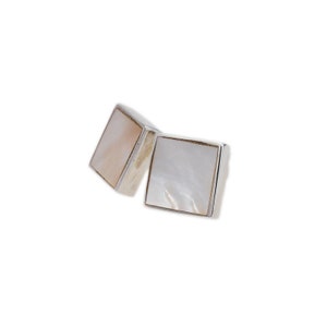 Può includere: Un paio di orecchini quadrati in argento con intarsi in madreperla.