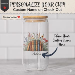 May include: A clear glass tumbler with a bamboo lid and glass straw, featuring a printed design of colorful wildflowers and a row of vintage books. The name Aurora is printed on the glass, with text reading PERSONALIZE YOUR CUP!