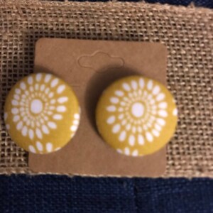 May include: A pair of mustard yellow fabric earrings with a white floral pattern.