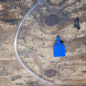Può includere: Un connettore in plastica blu con un tubo in plastica trasparente.