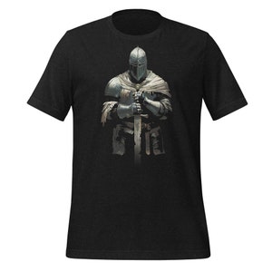 Könnte beinhalten: Schwarzes T-Shirt mit einer detaillierten Illustration eines mittelalterlichen Ritters in voller Rüstung, der ein Schwert hält. Der Ritter ist in Grau- und Silbertönen dargestellt, mit Helm und Kettenhemd. Das Design ist auf dem T-Shirt zentriert.