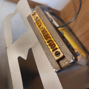 Handbrandstempel in den die Buchstaben einzeln einsortiert werden.