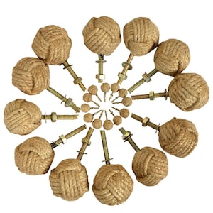May include: A collection of twelve drawer knobs arranged in a circular pattern. Each knob features a spherical head crafted from tan jute rope tied into a knot, attached to a threaded metal bolt with a washer and a hexagonal nut for installation.