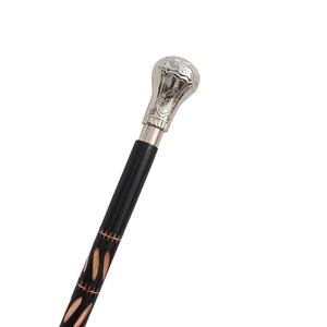 May include: A walking stick featuring a polished silver-tone metal handle with an embossed design. The shaft is made of black wood and is decorated with a series of vertical, light-colored wood inlays arranged in a repeating pattern along the length.