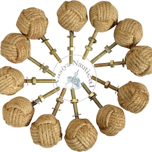 May include: A collection of nautical-themed cabinet knobs. Each knob features a tightly wound rope knot design in a natural tan color. The knobs are attached to brass-colored bolts with washers and nuts, creating a rustic aesthetic.