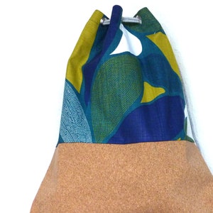 May include: A drawstring bag with a blue, green, and yellow floral pattern on the top half and a brown cork bottom.