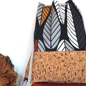 May include: A black drawstring bag with a cork bottom. The bag has a white and grey leaf pattern with orange accents.