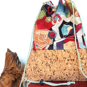 Peut inclure: Un sac à cordon avec un motif géométrique coloré sur la moitié supérieure et un fond en liège. Le sac a un cordon de serrage vert clair.