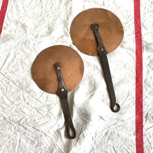 Peut inclure: Deux pelles à pizza anciennes en cuivre et en fer avec des lames rondes en cuivre et de longues poignées en fer.