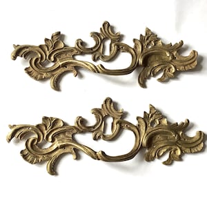 May include: A white ceramic mug with a black handle and the text "But First, Coffee" in a black, bold font. The mug is on a white surface.