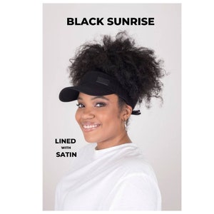 May include: A black visor with a curved brim and a small rectangular patch. The visor is lined with satin and has the text "BLACK SUNRISE" at the top. The text "LINED WITH SATIN" is also visible.