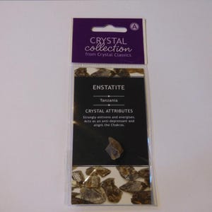 Könnte beinhalten: Eine Verpackung aus der Crystal Collection mit Enstatit-Kristallen. Die Verpackung hat eine lila Kopfzeile mit dem Text "Crystal Collection from Crystal Classics". Die Karte im Inneren trägt den Text "ENSTATITE Tanzania CRYSTAL ATTRIBUTES".