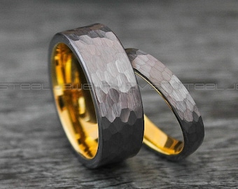 May include: Two wedding bands, one with a hammered black finish and the other with a gold finish.